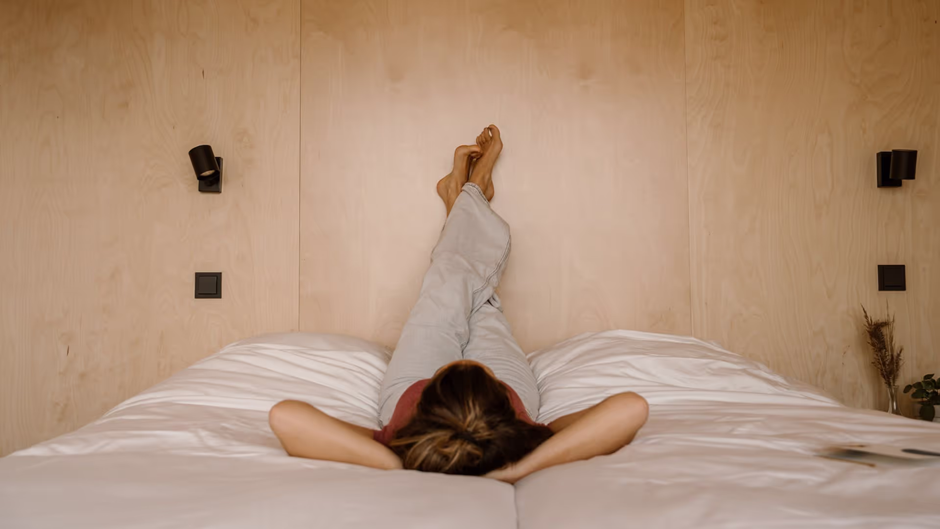 Persoon met benen gekruist omhoog op bed tegen de muur van een Havenkamer