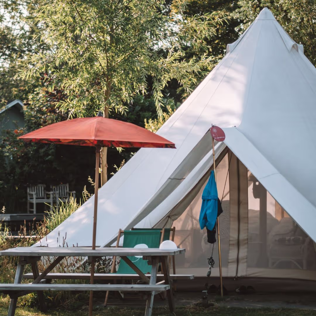 De Zwiertent van buiten met een picknicktafel en een parasol.