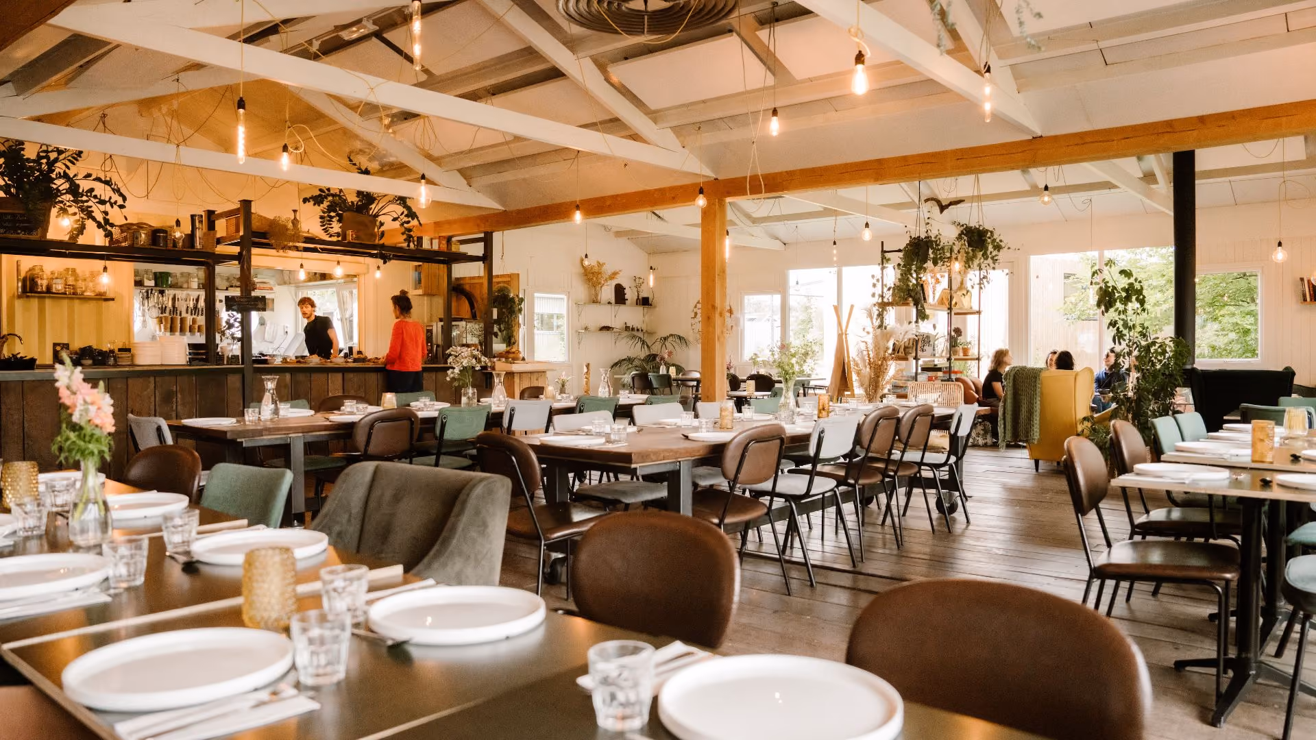 Ruime eetzaal met gedekte tafels en open keuken