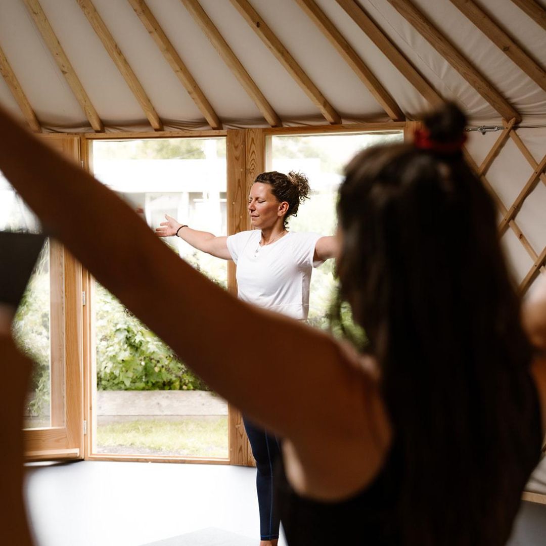 Groep die yogaoefeningen doet in een yurt