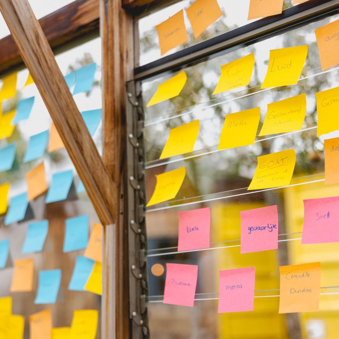 Post-its met woorden op een glazen wand tijdens een brainstorm
