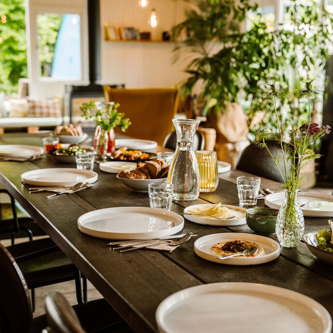 Lang gedekte ontbijttafel met brood en salades