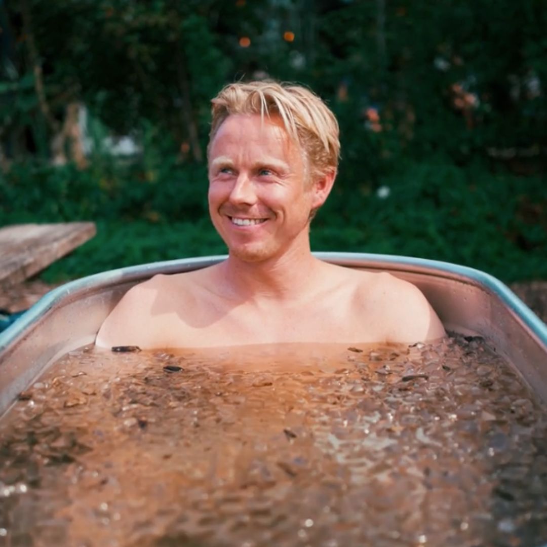 Man die glimlacht in een ijsbad in de tuin