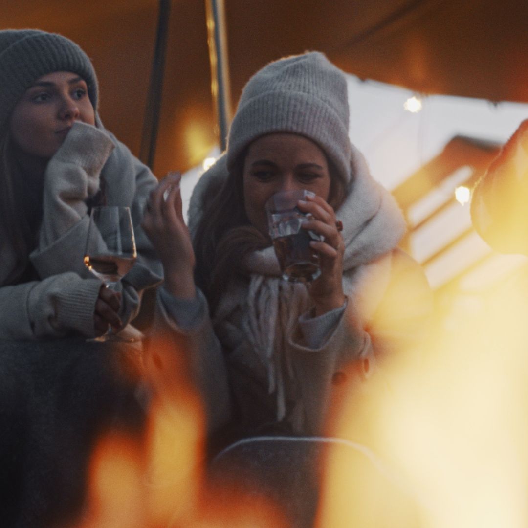 Twee vrouwen die drinken bij het vuur in de avond