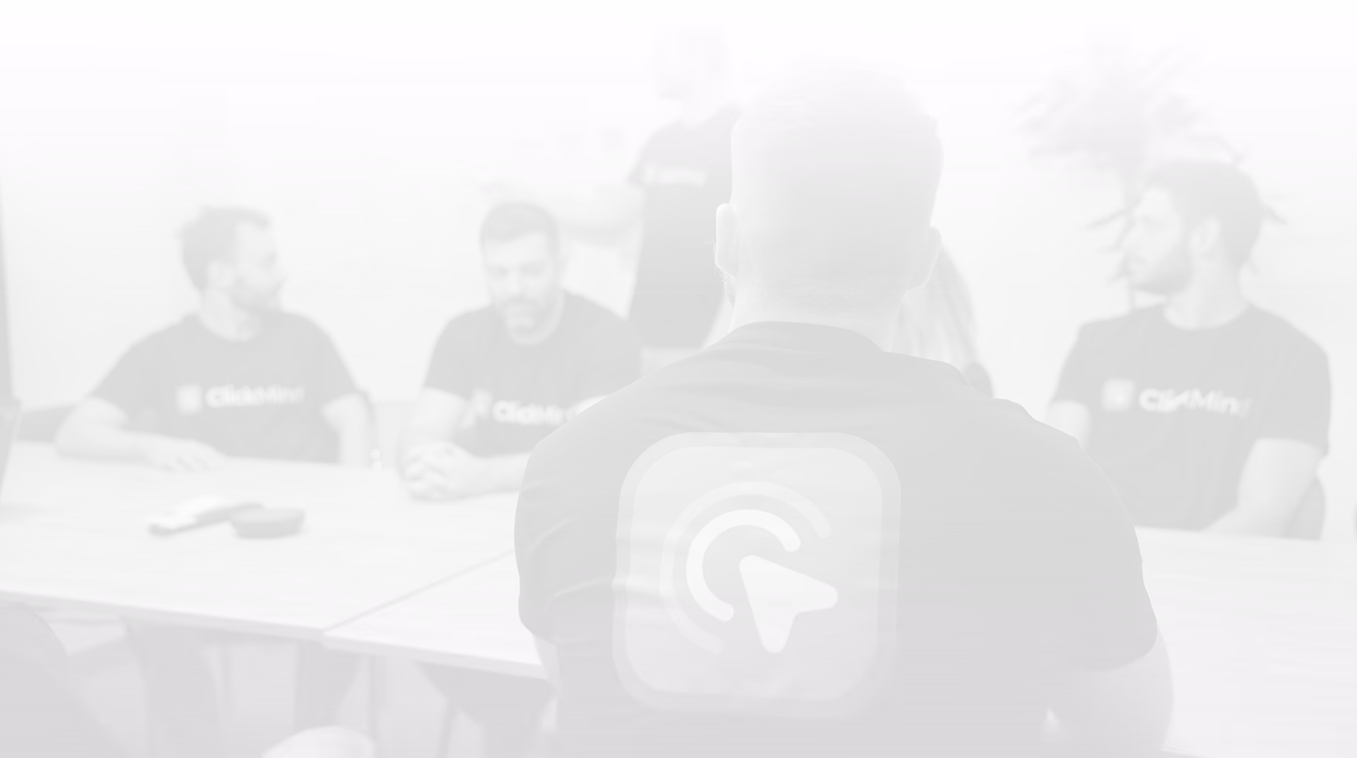 Group of five people in matching ChatMind shirts sitting around a table in a meeting room.