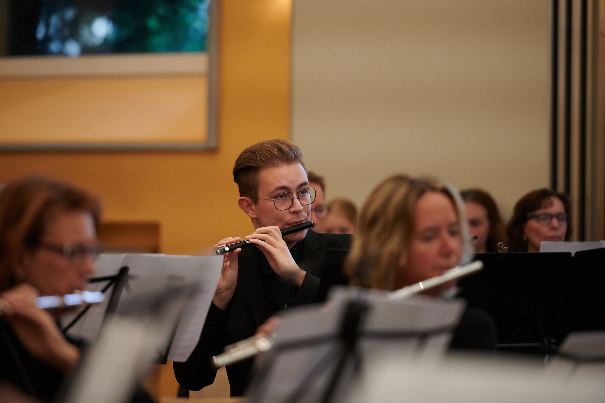 Flötist des Perflu Orchesters bei einer Konzertaufführung, umgeben von weiteren Musizierenden