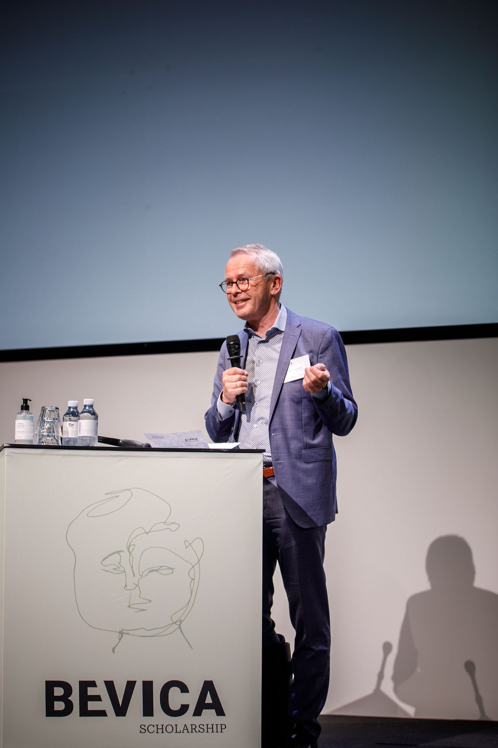 Forperson for Bevica Fonden står på en scene foran en pult medfondens logo på.