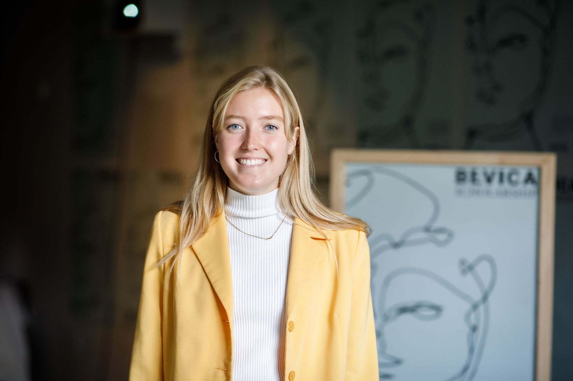 Foto af Daura der smiler. Hun har en hvid trøje og en gul jakke på