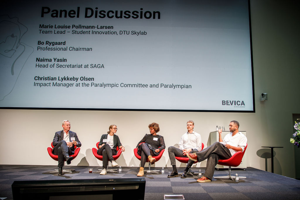 Fire debatdeltagere sidder på en scene