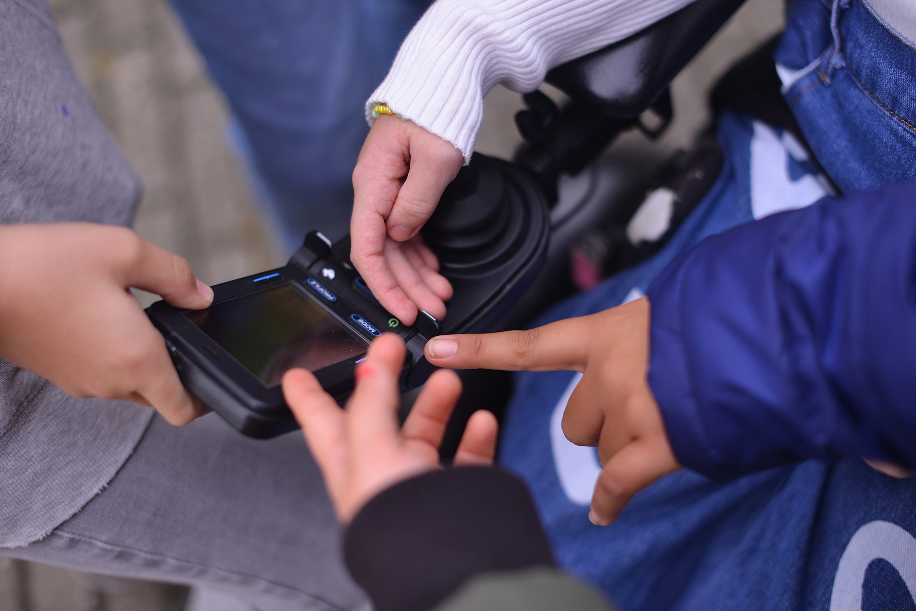 Børnehænder styrer en elektrisk kørestol