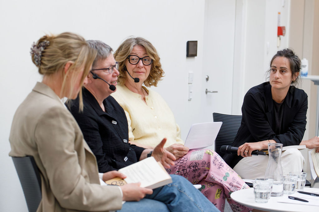 Publikum sidder foran scene med fire mennesker i et panel