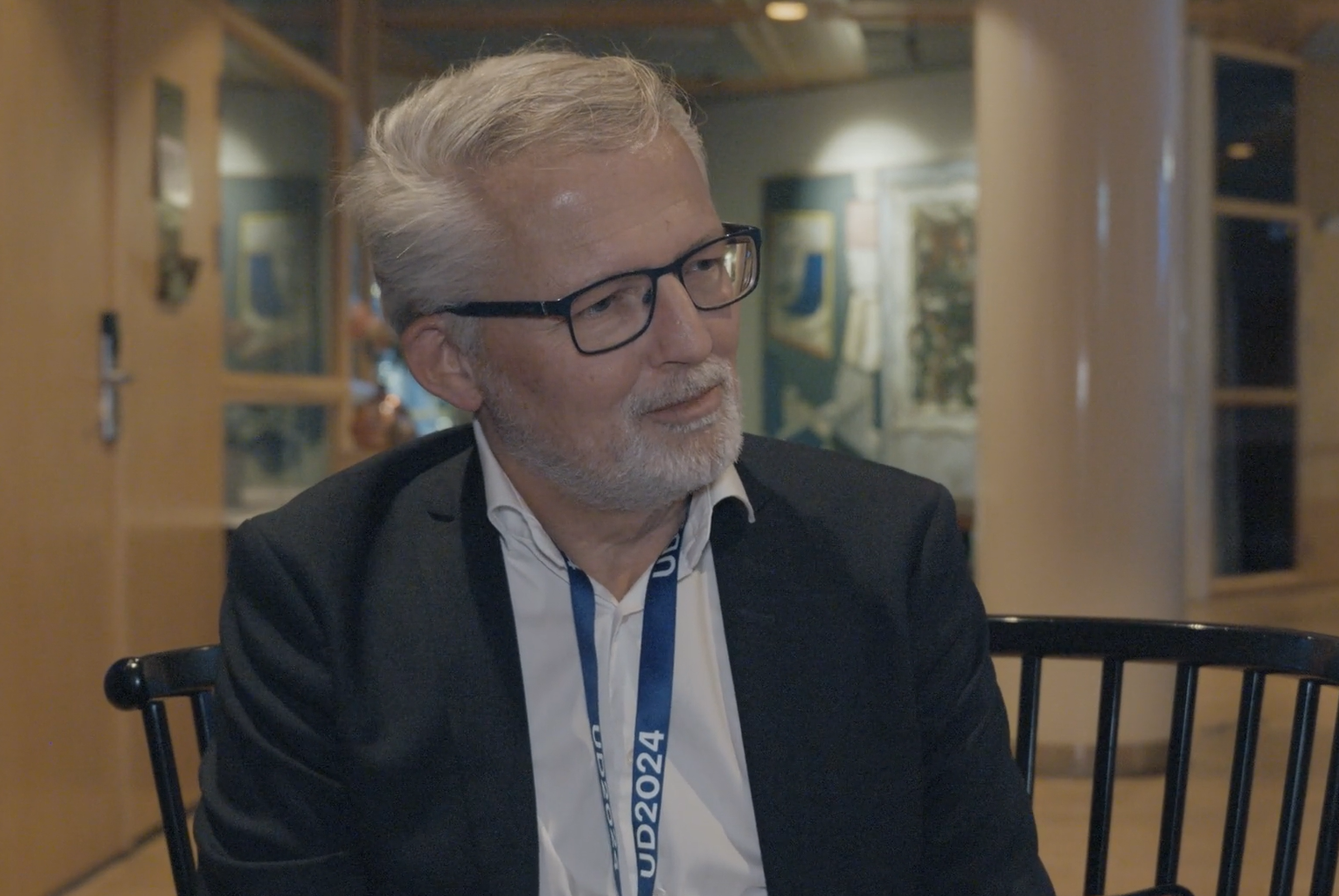 Bent Madsen being interviewed. He is wearing a white shirt and a black blazer. 