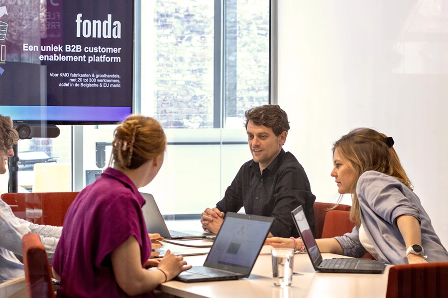 Fonda team zit in een vergaderzaal met hun laptops