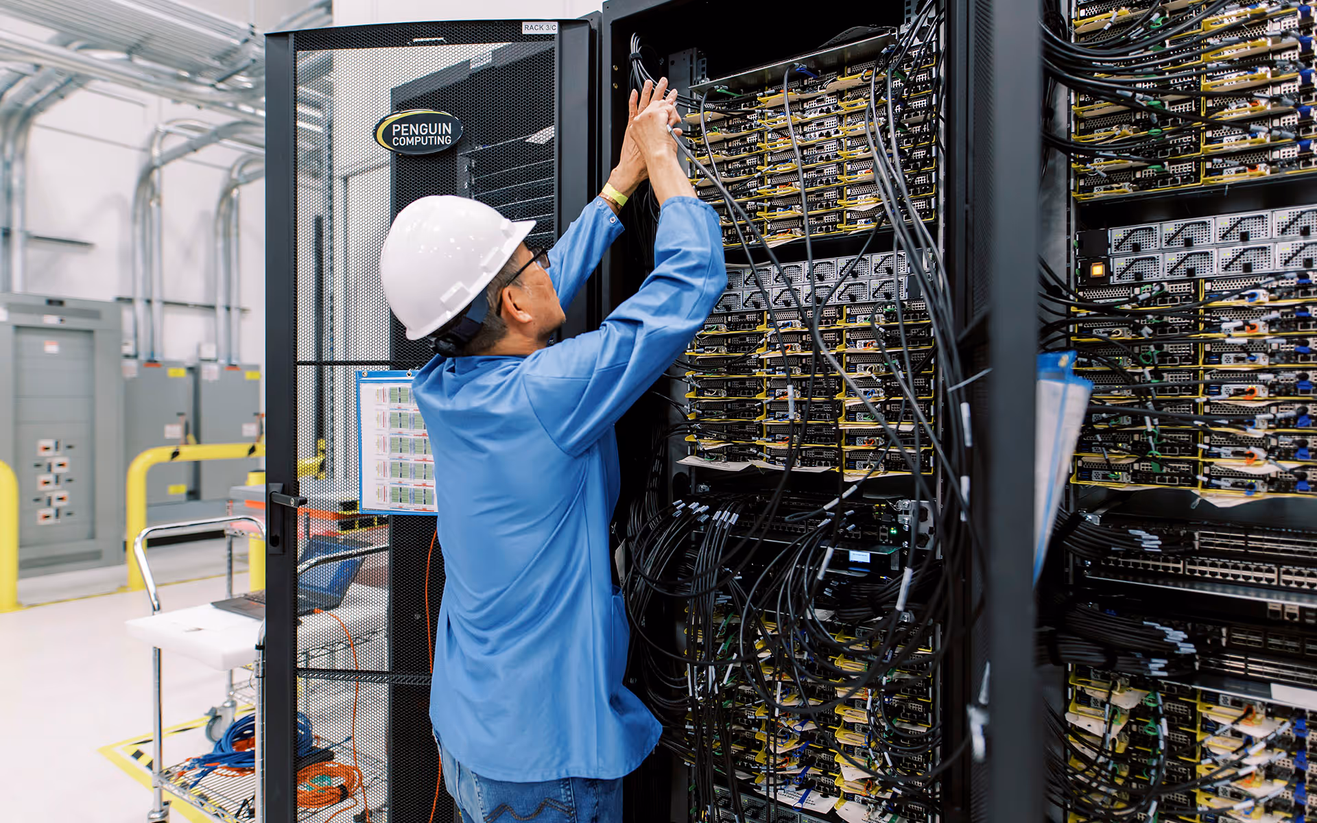 Worker adding cabling to server cage