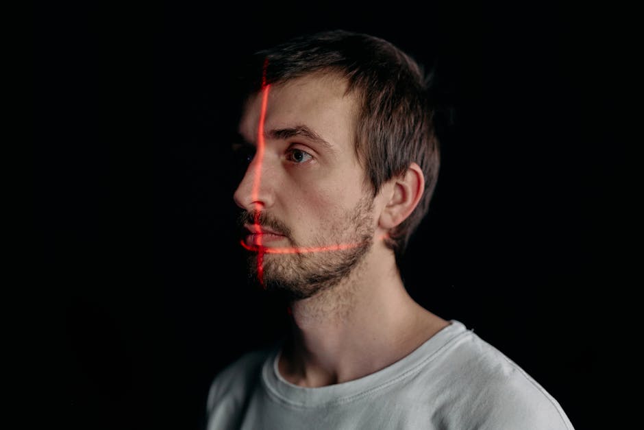 A man undergoes a facial recognition scan with a laser grid in a studio setting.