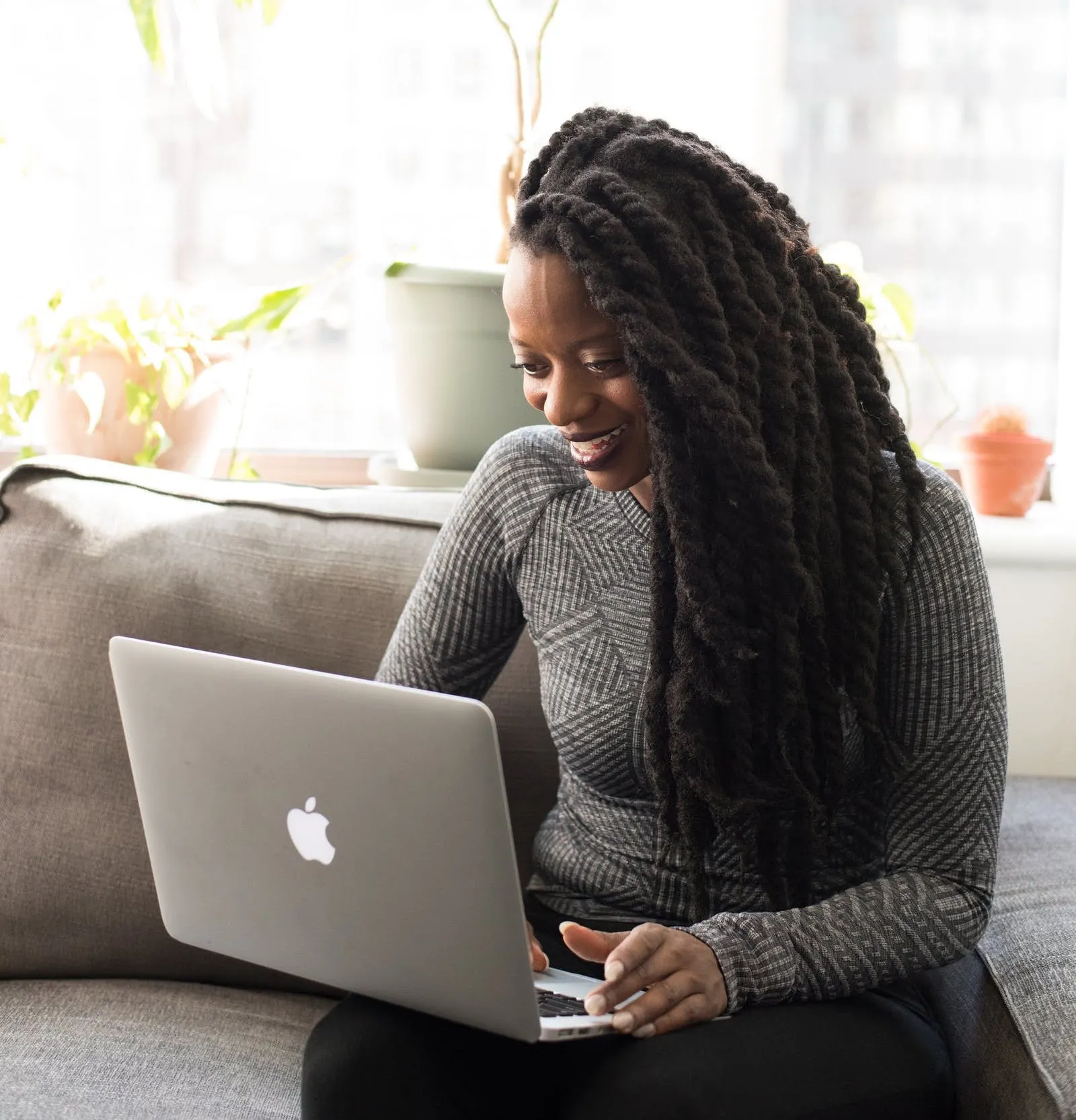 Person sitting on a couch using a laptop in a bright home setting