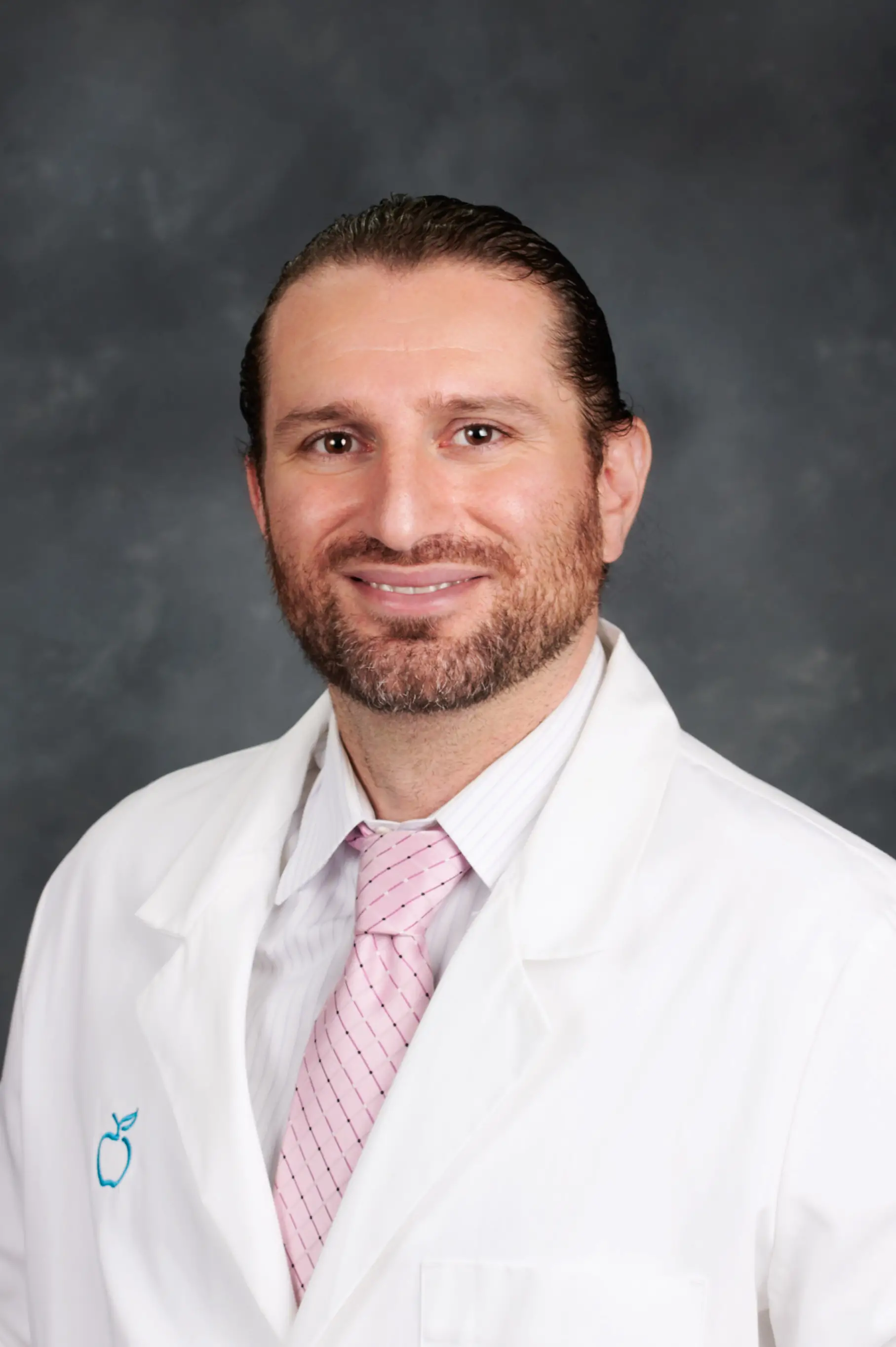 Medical professional in a white coat smiling in a studio portrait