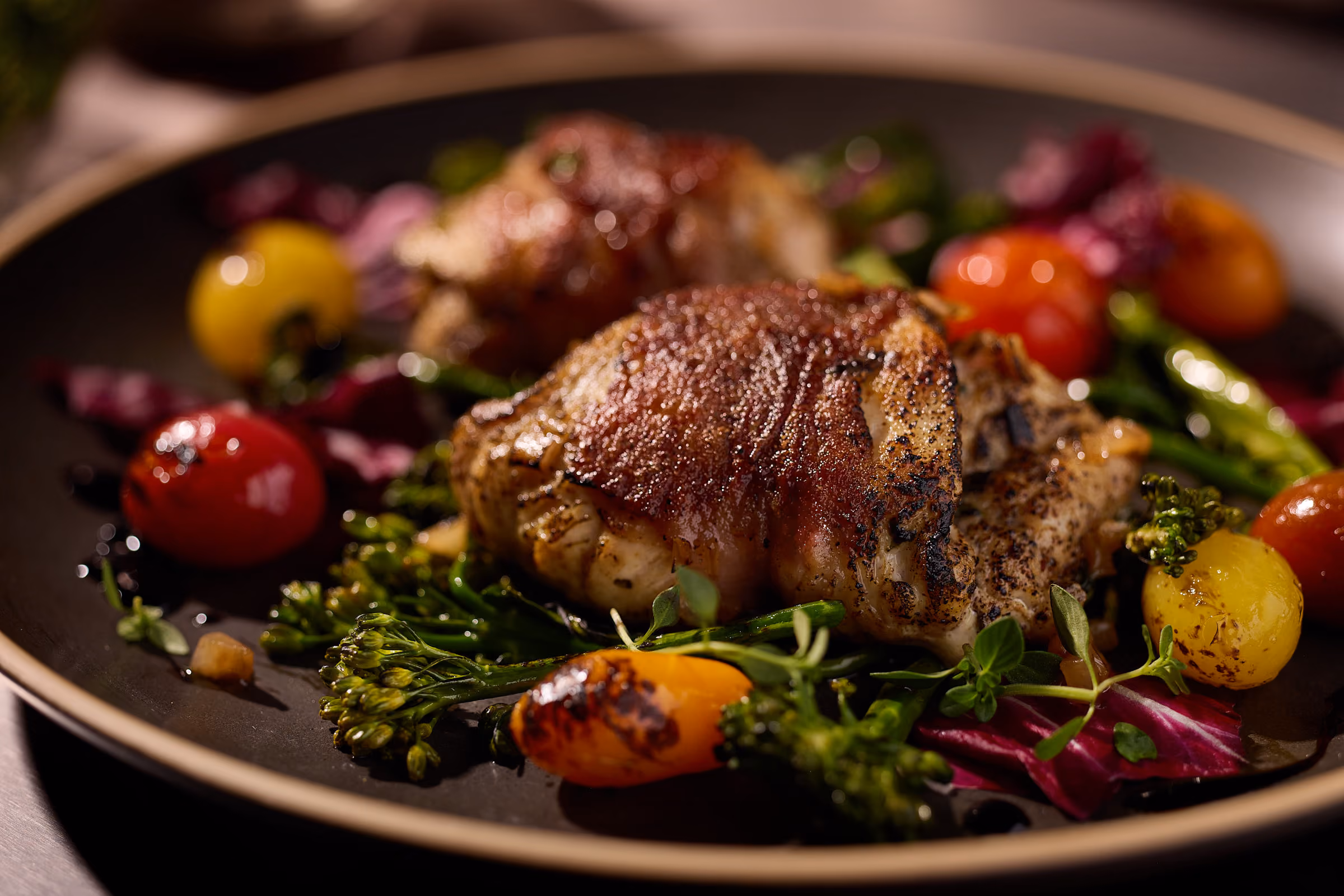 Two golden-brown chicken legs stuffed with green spinach and feta mixture on a brown plate.