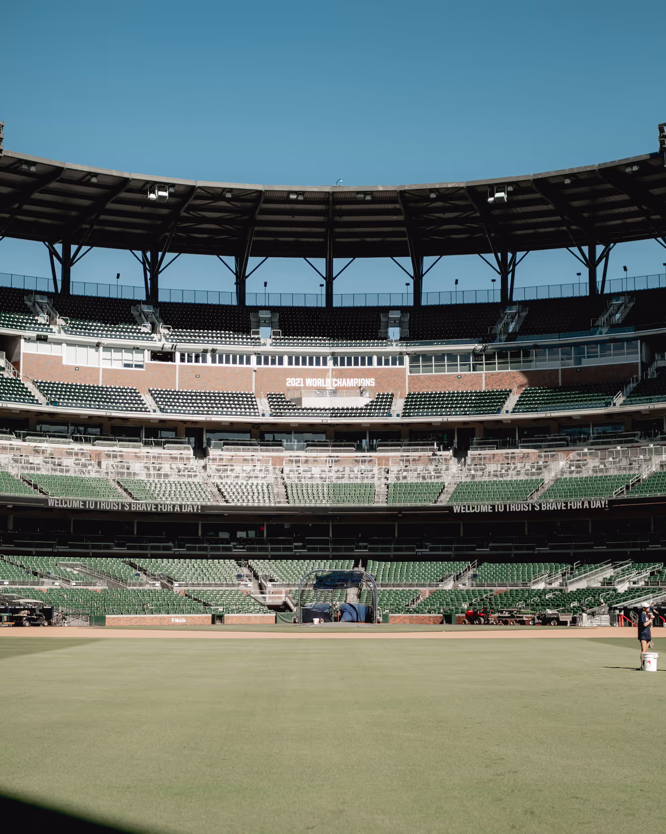A view of an empty baseball stadium from the outfield towards the infield on a sunny day.