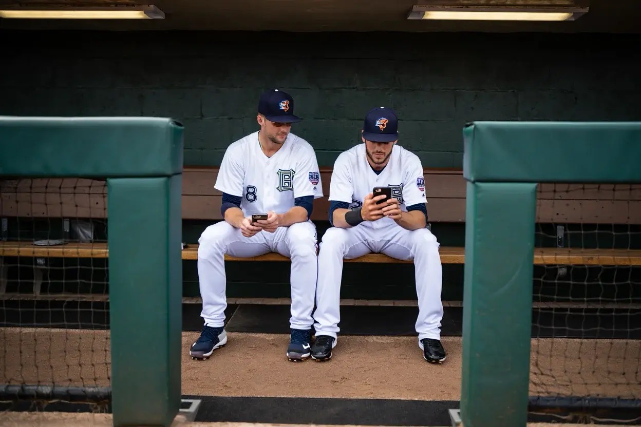 Baseball players in the dugout looking at their statistics