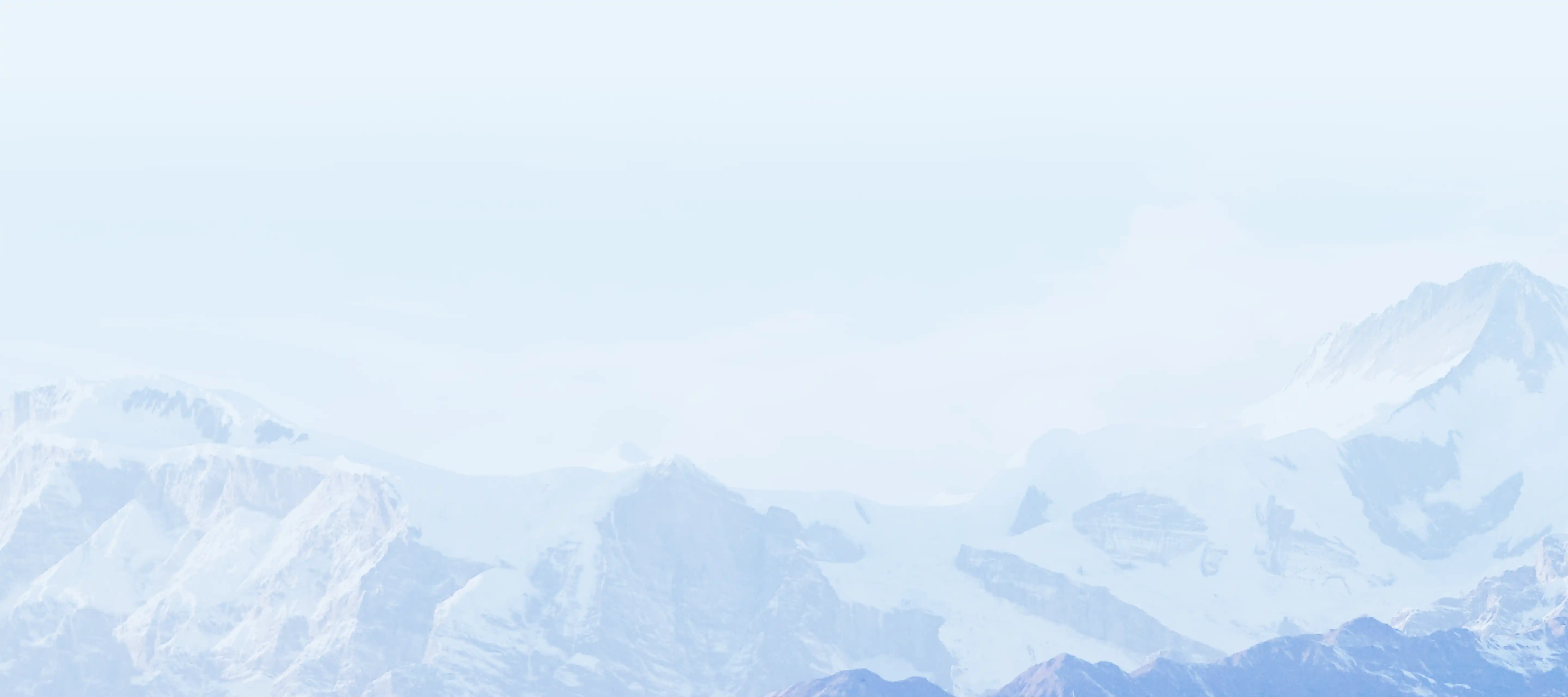 Snow-covered mountain range under clear, pale blue sky.