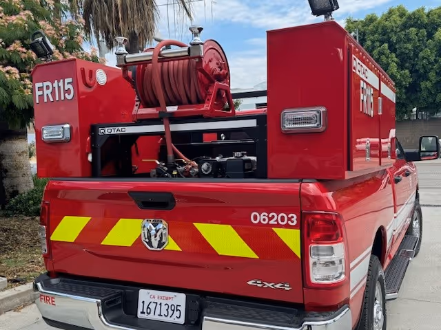 The back of a pickup truck equipped with a pump, hose, and other necessary equipment.