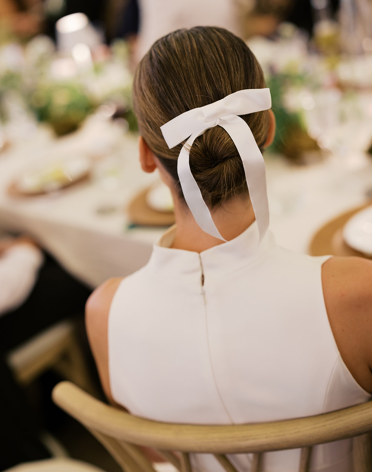 Bride seated at the reception wearing a minimalist gown with ribbon detail during a luxury Sun Valley wedding.