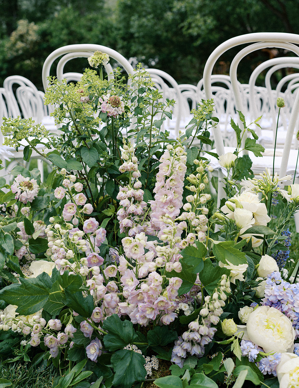 Lush garden-inspired ceremony arrangements with peonies, delphinium, and greenery at Trail Creek Cabin in Sun Valley