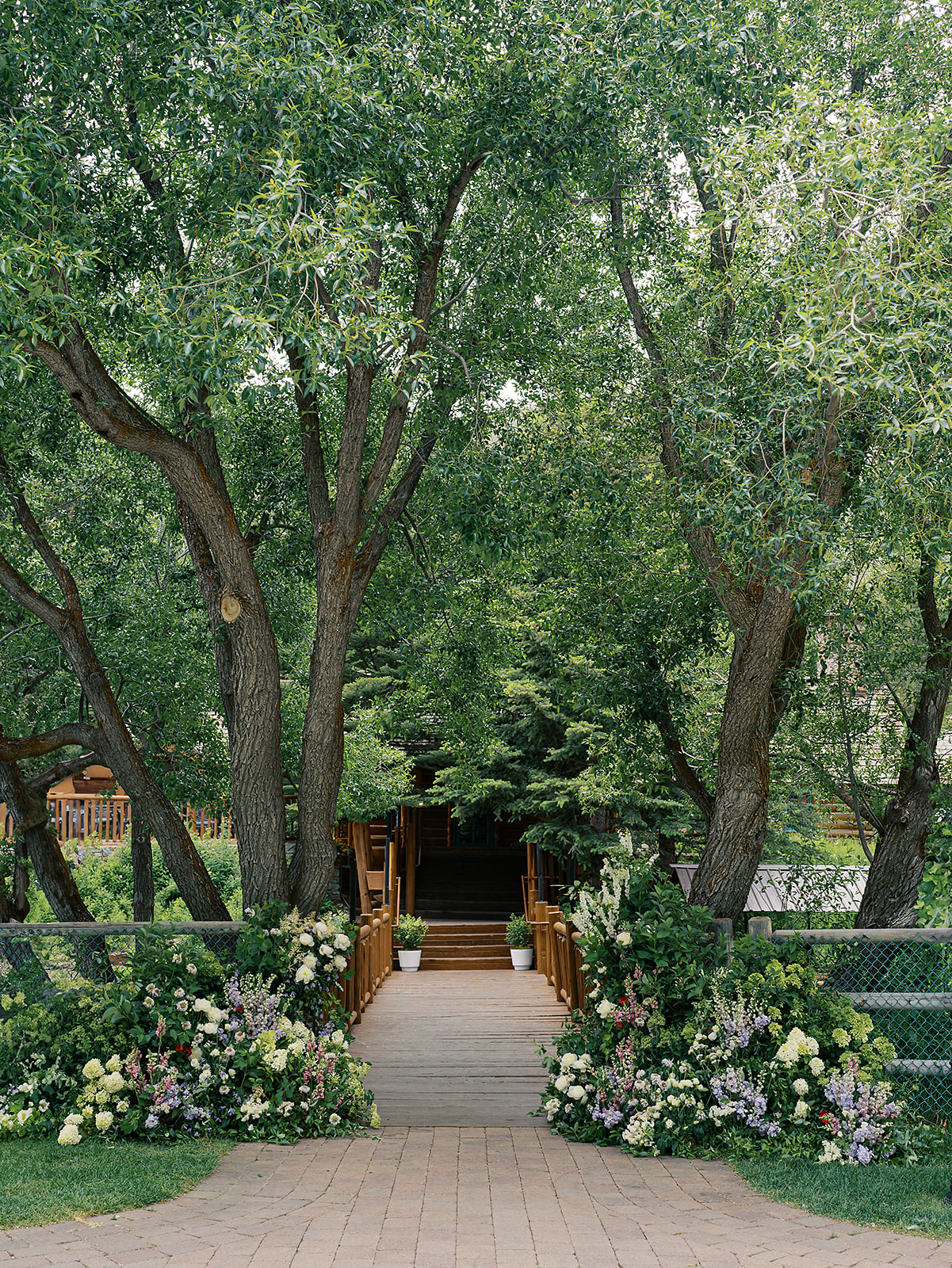 Garden-style floral arrangements flanking the bridge ceremony at Trail Creek Cabin wedding in Sun Valley, Idaho