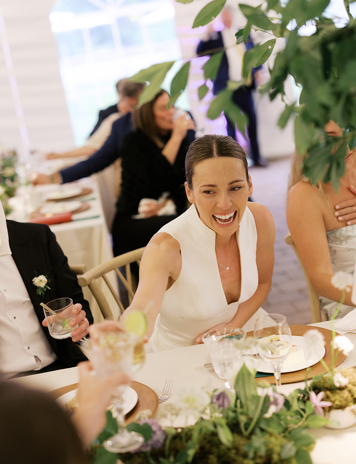 Bride laughing and toasting guests during a joyful Sun Valley wedding reception surrounded by lush floral design.