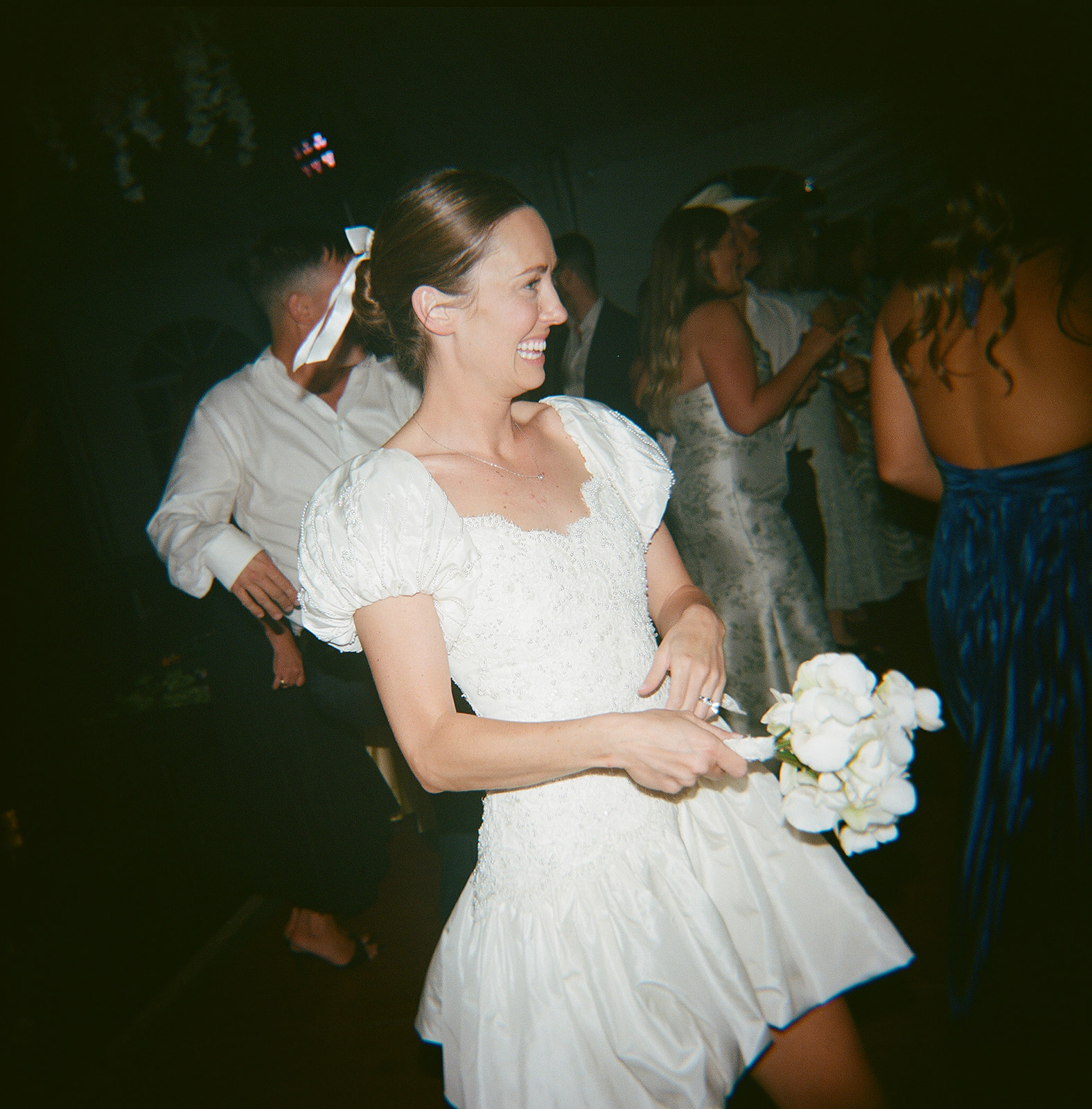 Bride dancing in a custom party dress during a Sun Valley wedding reception, surrounded by guests and glowing lights.