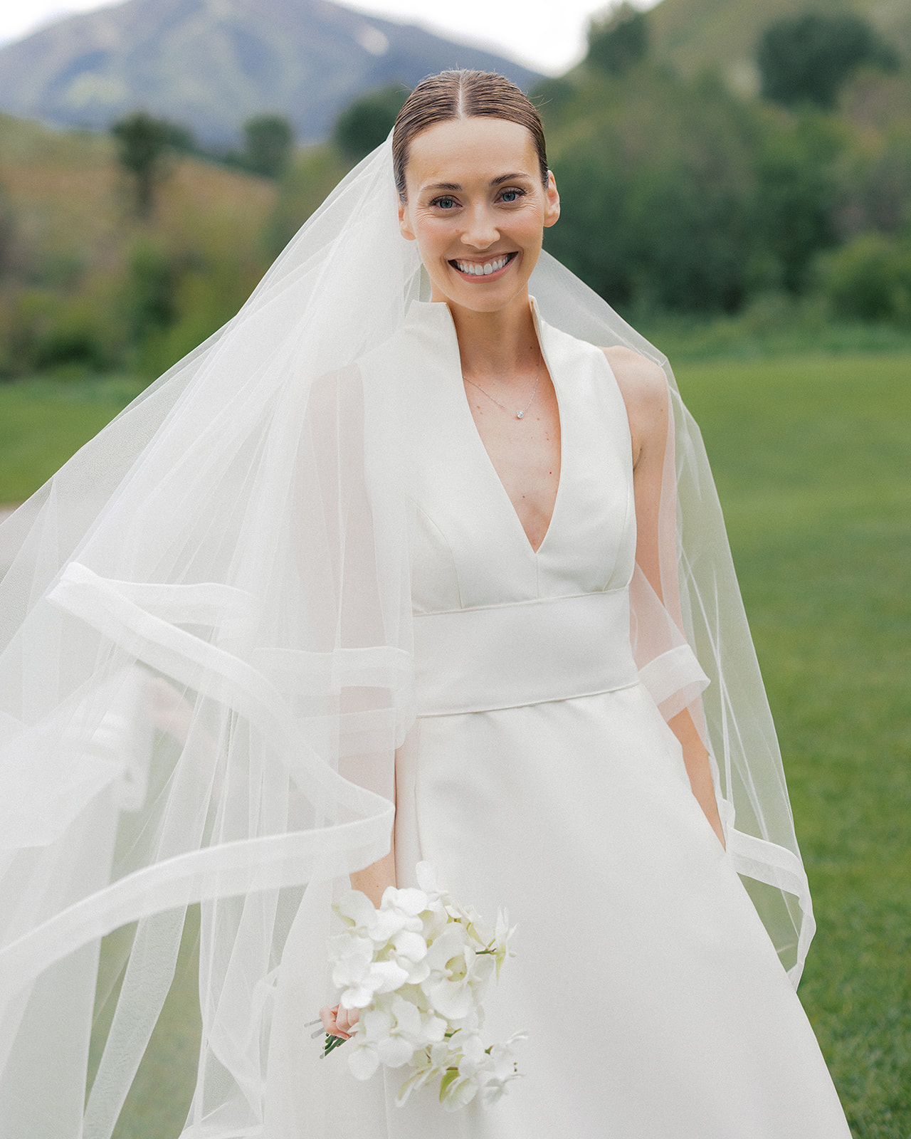 Bride holding a petite phalaenopsis orchid bouquet at a Sun Valley wedding with mountain scenery in the background