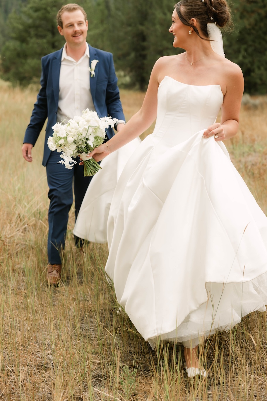 Bride and groom walking in grassy field McCall wedding