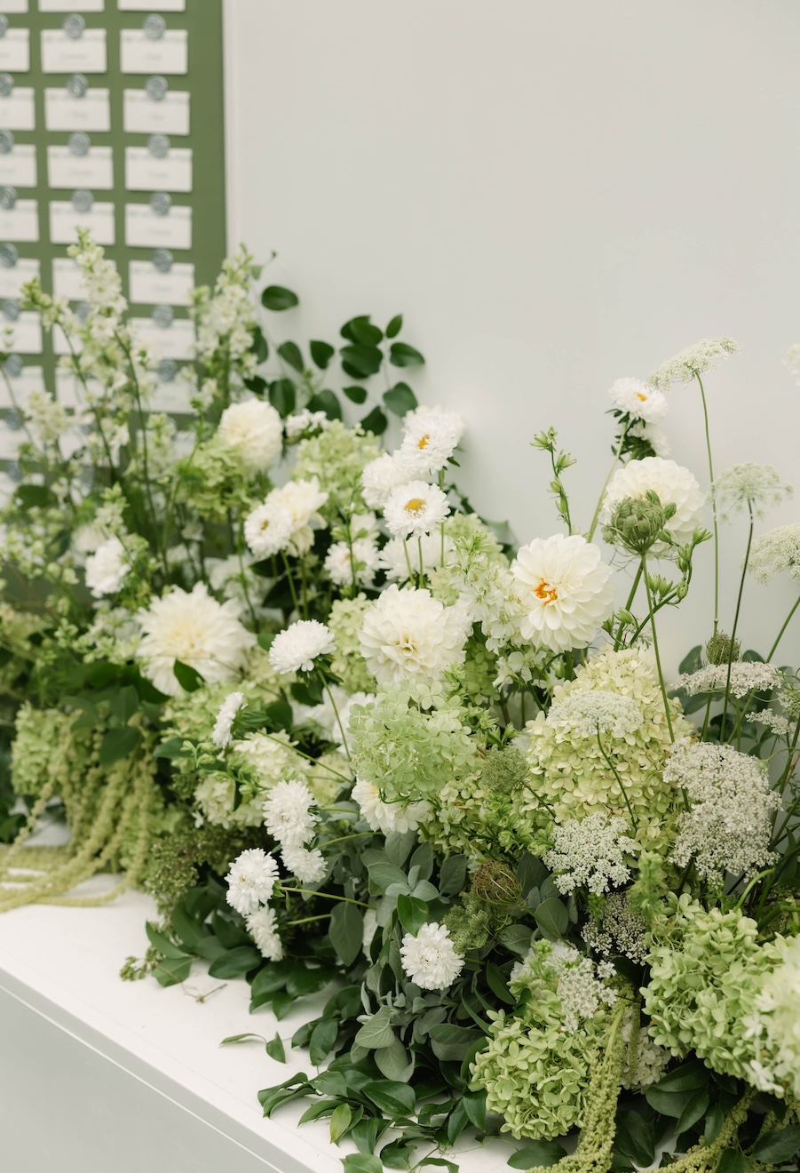 Lush florals in front of seating chart at McCall wedding