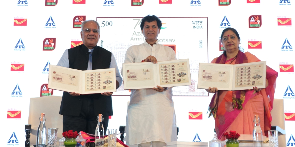 Three people standing on stage presenting the ITC Foods millets stamps
