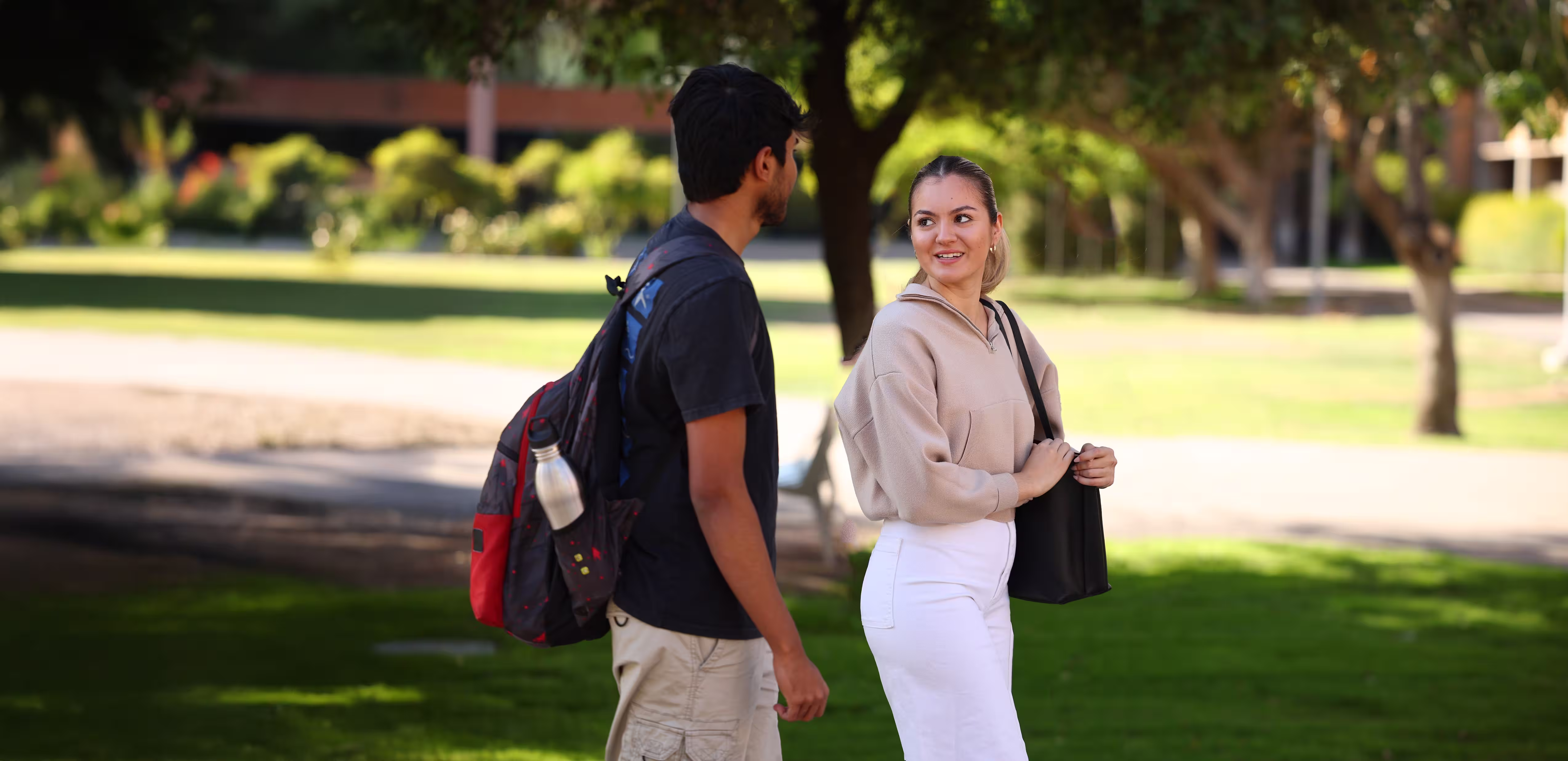 Two students walking and talking on a campus. 