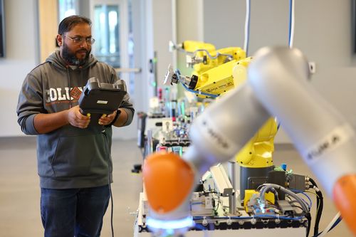Individual using a tablet and working on a set of robotic arms.