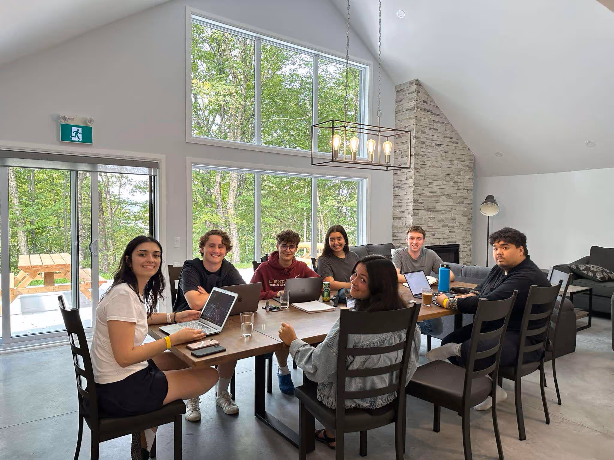 photo des membres de la cjplq réunis travaillant autour d'une table dans une grande salle a manger avec leurs ordinateurs d'ouvert