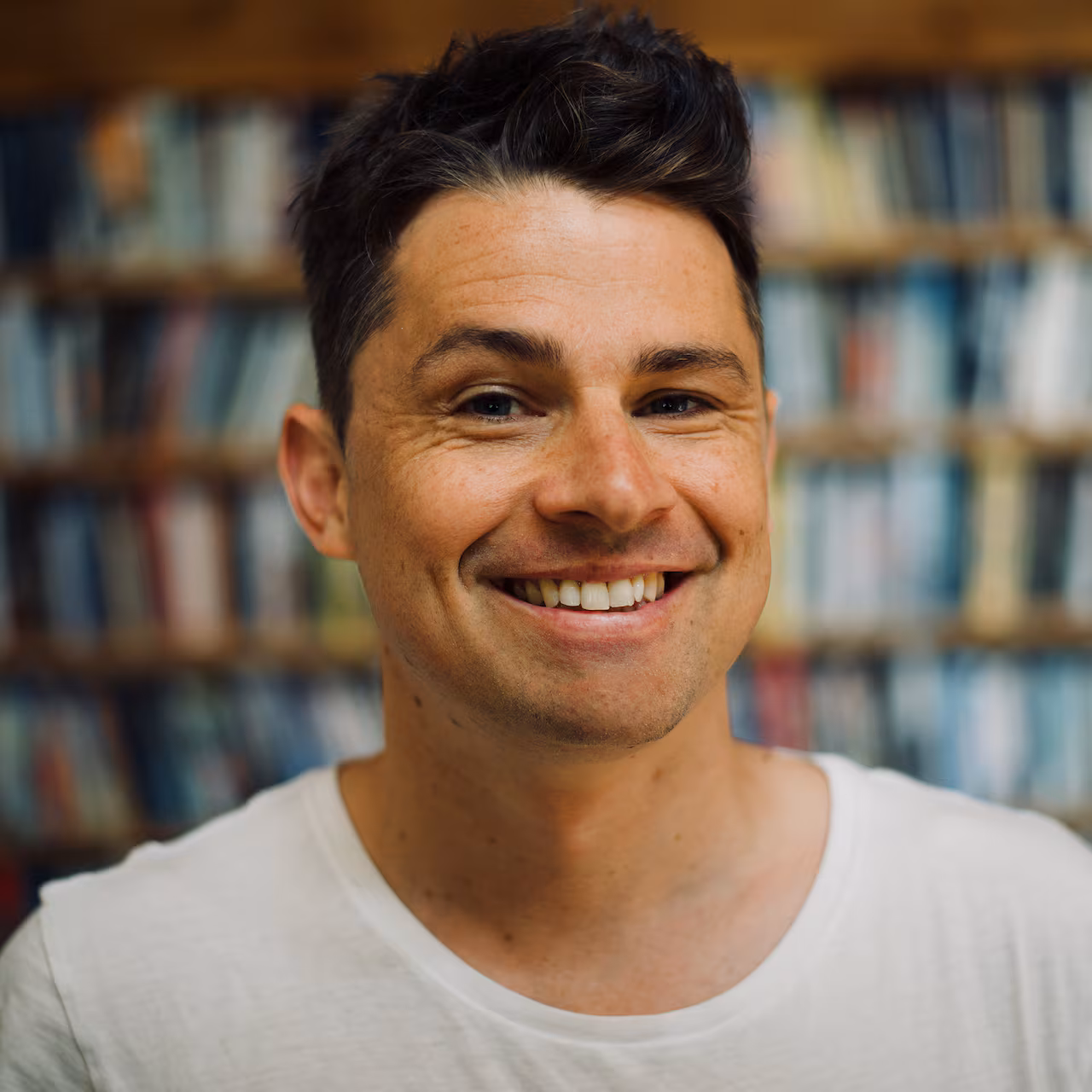 Headshot of Canadian author Michael Christie, smiling, outdoors with natural greenery in the background.