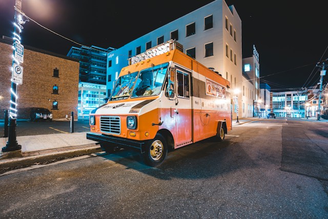 Orange and white food truck parked on a city street at night in California