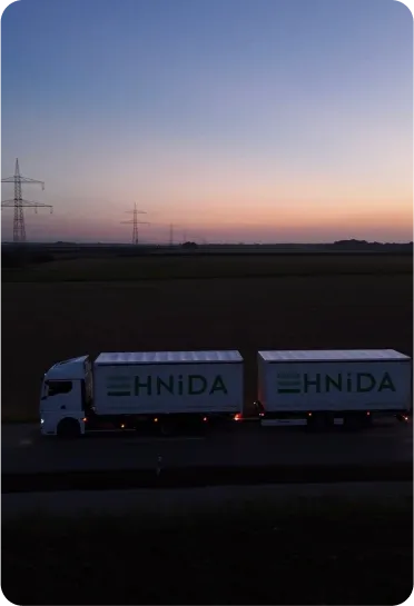 HNiDA-Lastzug mit eingeschalteten Lichtern bei Sonnenuntergang