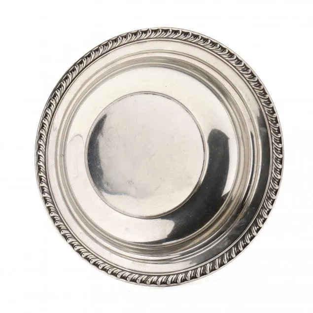 Round silver plate with decorative rope-like border and reflective surface.
