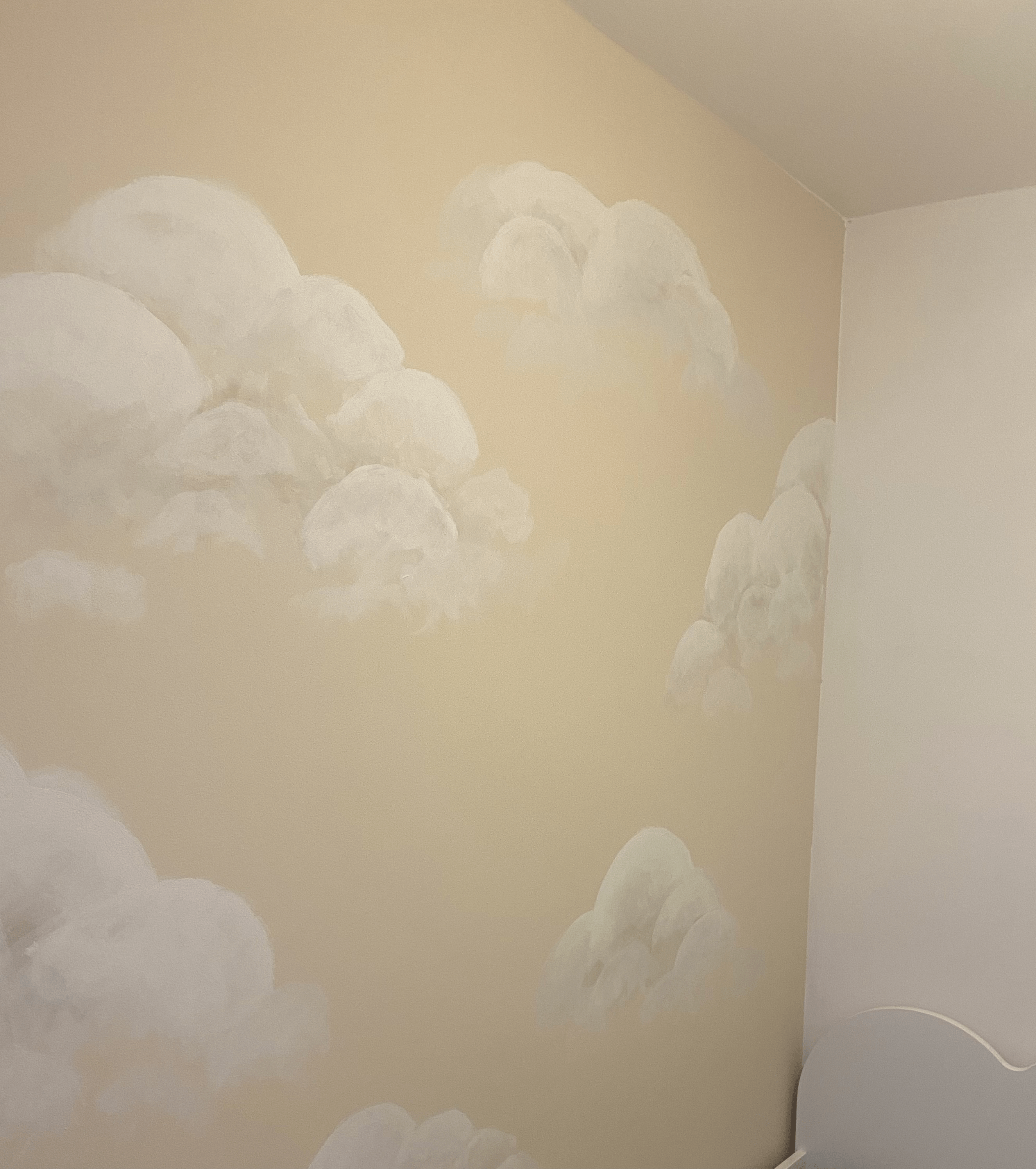 Wall mural of soft, white clouds painted on a beige interior wall.