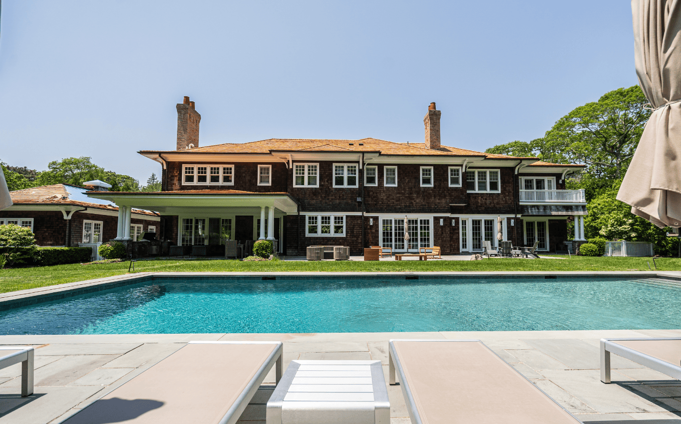 Luxury Long Island home with cedar roofing, spacious backyard, and swimming pool, showcasing premium roofing and siding craftsmanship