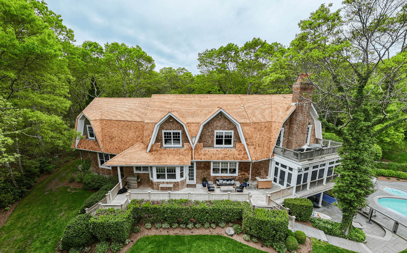 Aerial view of the cedar shake roof installation at the 1010 Seven Ponds project by Cedar Solutions Roofing, showcasing the detailed craftsmanship on a large Long Island home surrounded by greenery.