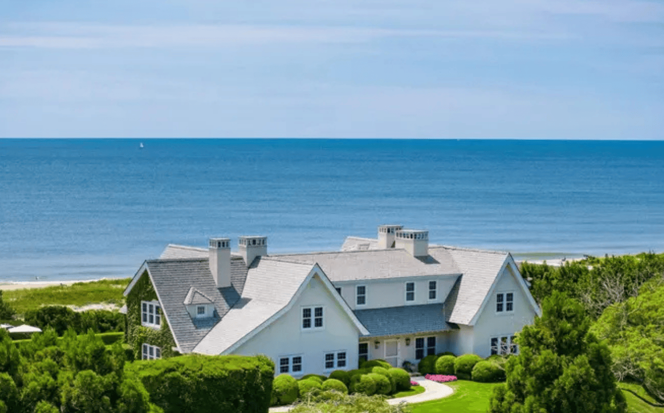 Hamptons coastal home overlooking the ocean with a bright roofline and manicured landscaping