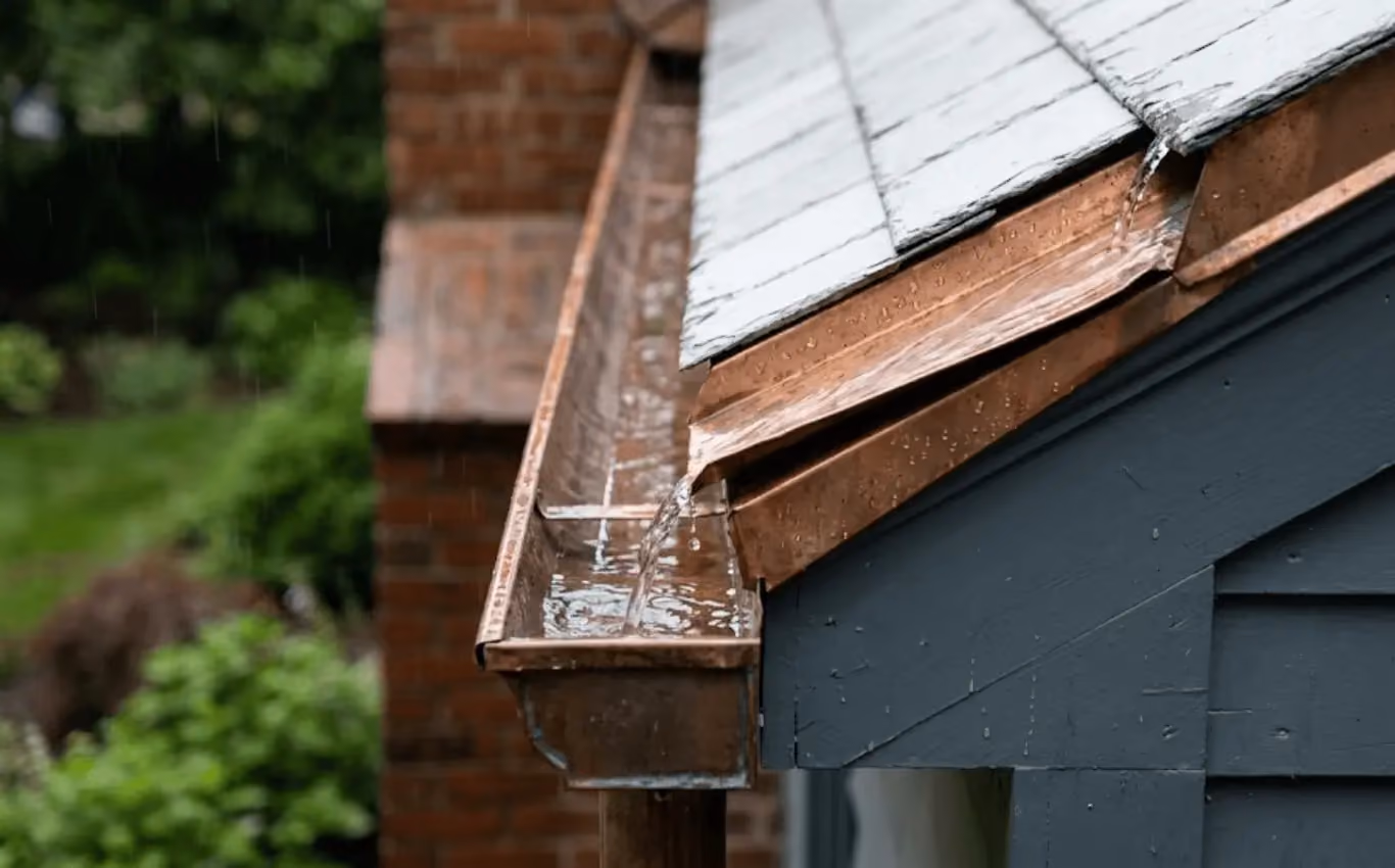 Close-up of roof edge with custom metal flashing and gutter guiding rainwater for proper drainage.