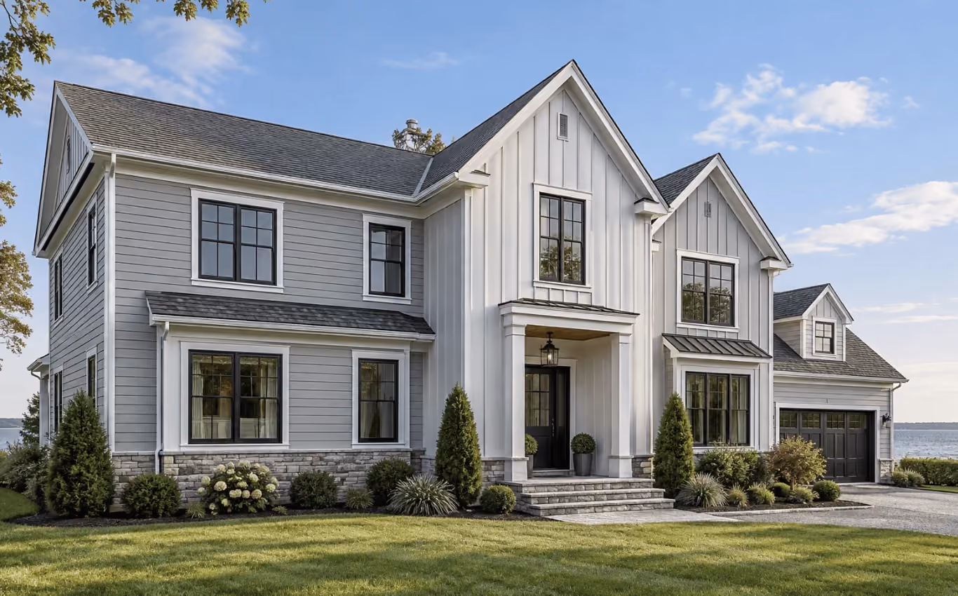 Modern Long Island home with gray horizontal siding, white vertical board-and-batten siding, black-framed windows, and stone accents.