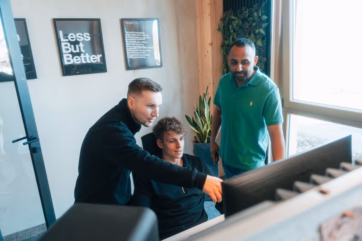 Drei Männer arbeiten zusammen im modernen Büro mit Motivationsplakat