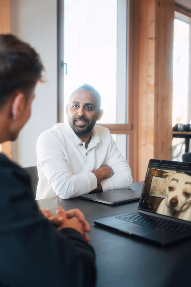 Zwei Personen in einem Büro während eines Gesprächs, Laptop mit Hundefoto